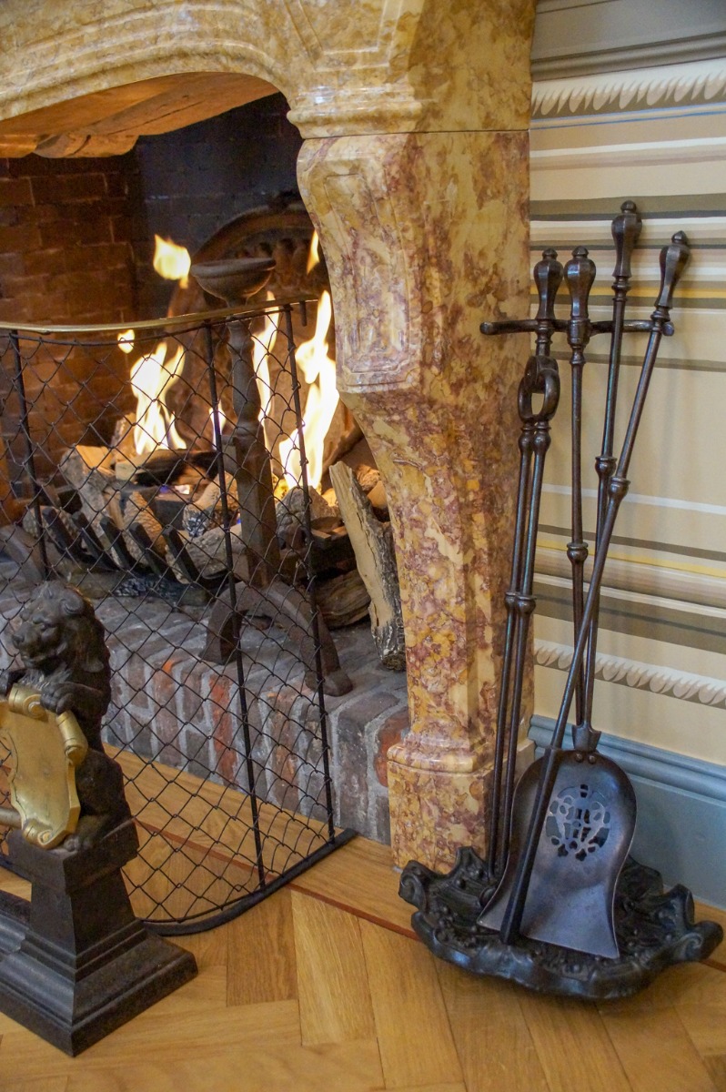 Gas fireplace decorated as wood-burning fireplace with antique firedogs