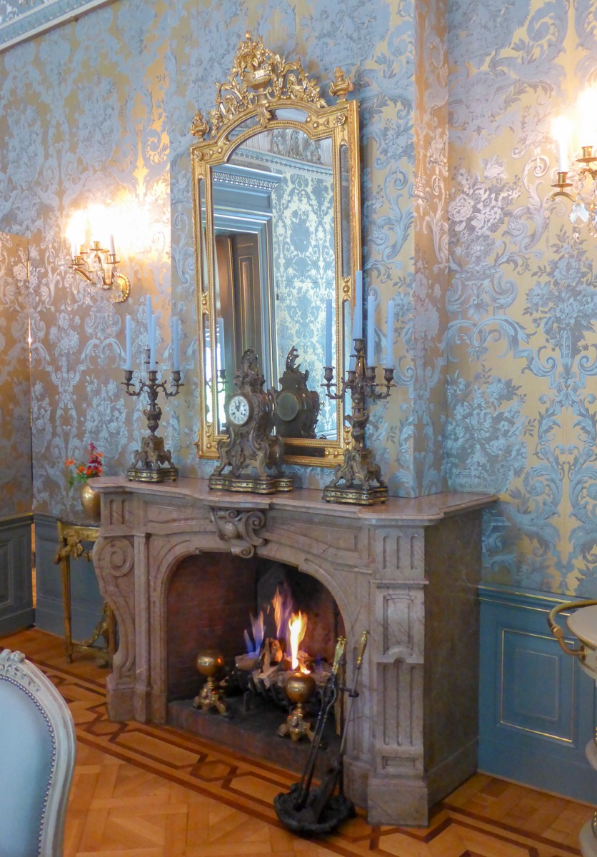 Gas fireplace decorated as wood-burning fireplace with antique firedogs