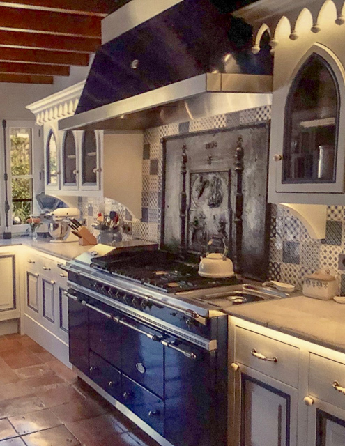 Large antique French fireback over a stove in a monumental kitchen