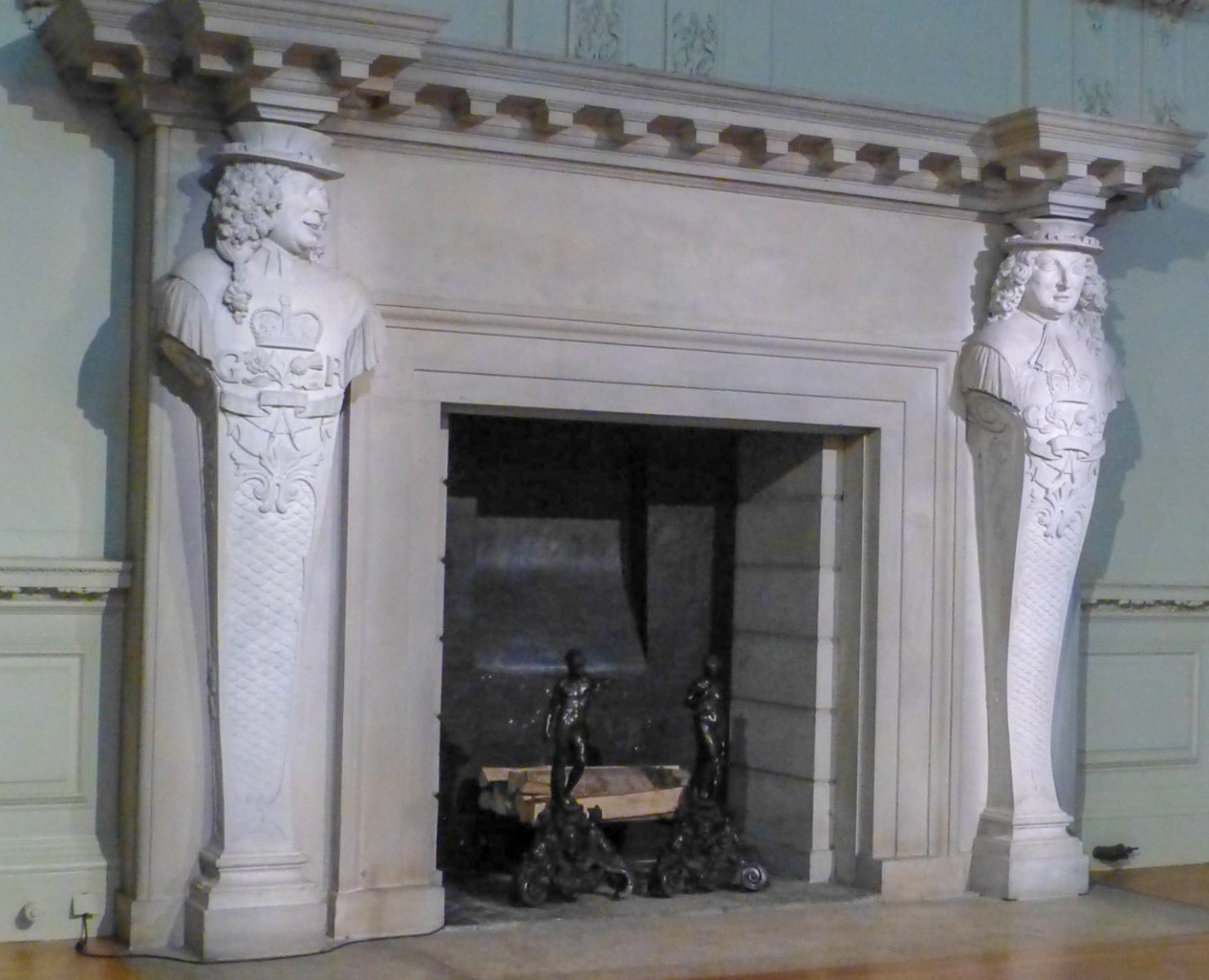 Gas fireplace decorated as a wood-burning fireplace with antique andirons