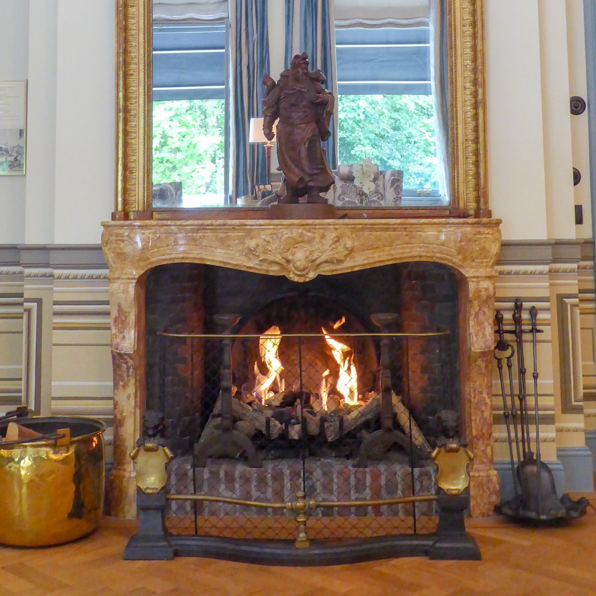 Gas fireplace decorated as wood-burning fireplace with antique andirons