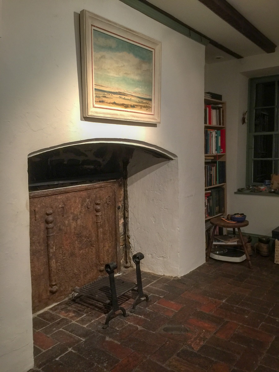 An unused, colonial fireplace in the New York area with a sturdy French fireback