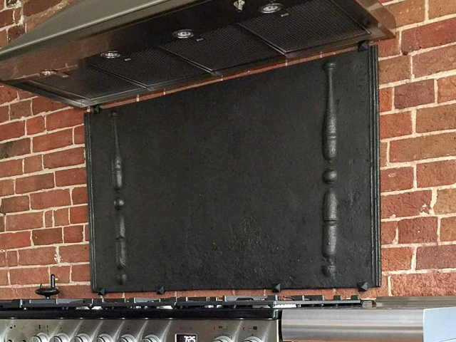 Wall-mounted fireback backsplash with mounting brackets