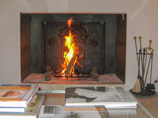 A modern Spanish fireplace with a 17th century French fireback and 19th century andirons